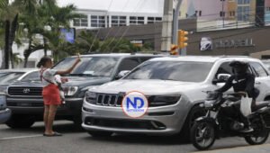 Joven con uno de sus niños en brazos vende dulces en La Lira